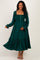 woman wearing a dark green maternity dress with a smocked bodice, long sleeves, and a tiered skirt, holding her baby bump