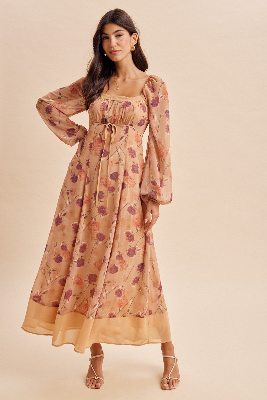 woman wearing a floral print maxi dress with long puff sleeves and a square neckline, standing against a light background