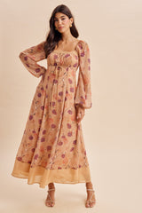 woman wearing a floral print maxi dress with long puff sleeves and a square neckline, standing against a light background