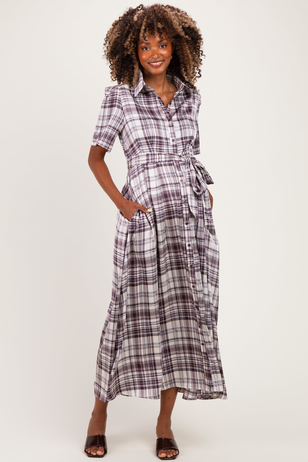 woman wearing a purple and white plaid maternity maxi dress with short sleeves and a tie waist, showing her baby bump