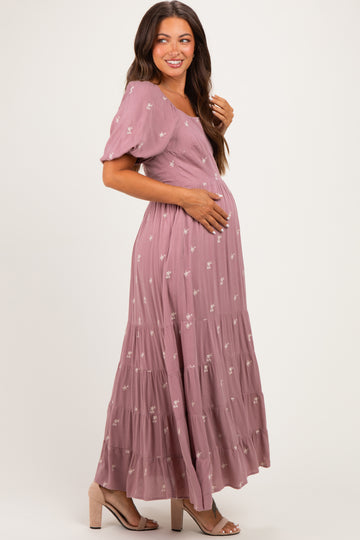 woman wearing a dusty rose maternity maxi dress with floral details and holding her baby bump