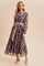 woman wearing a dark floral maxi dress with a pink tie belt and long sleeves