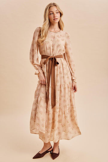 woman wearing a floral printed long sleeve maxi dress with a tied waist belt and pointed toe heels
