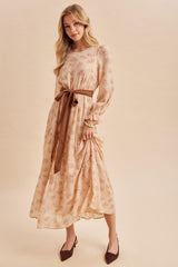 woman wearing a light peach floral maxi dress with long sleeves and a brown belt, paired with matching heels