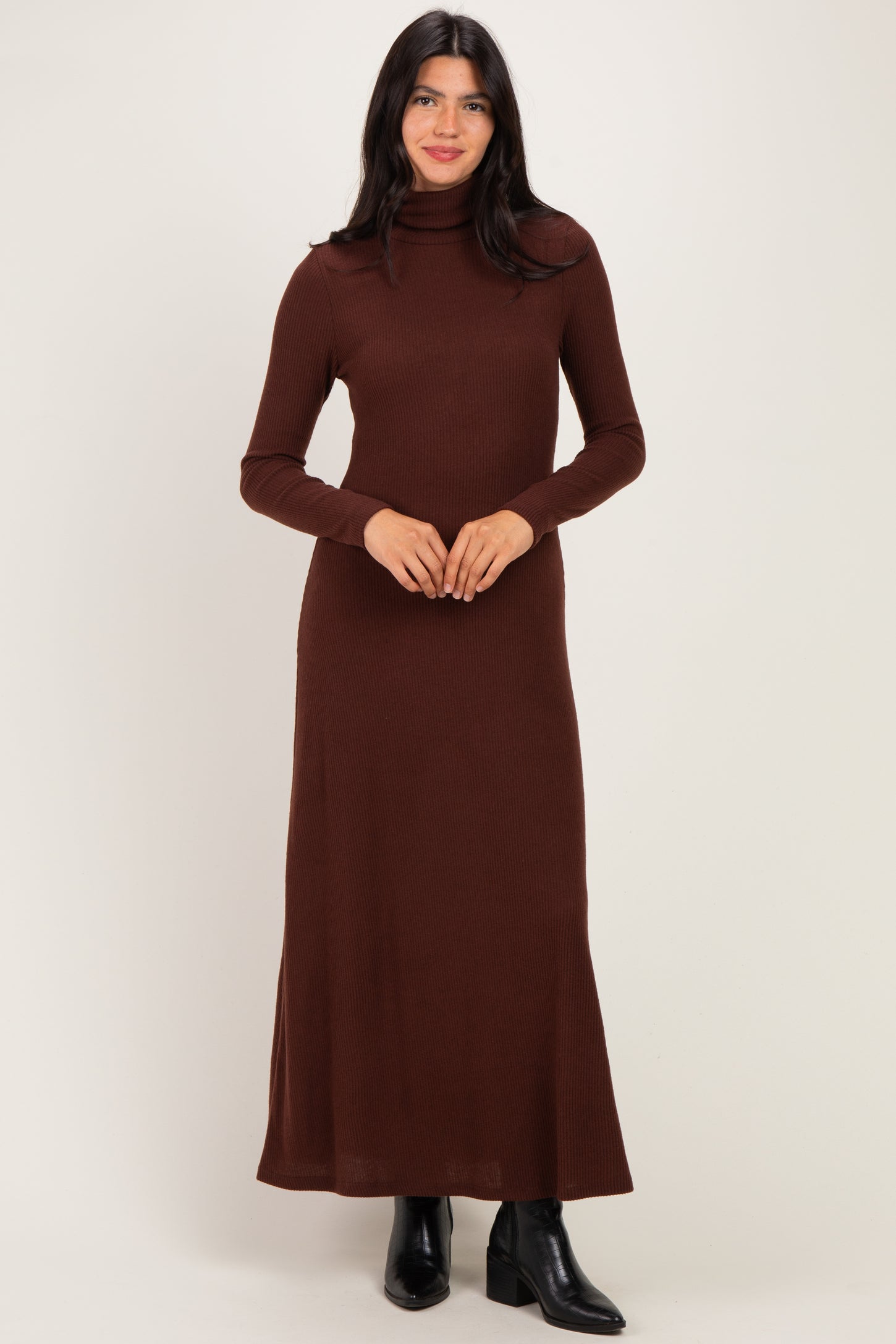 woman wearing a rust long sleeve turtleneck maxi dress with a fitted silhouette and flared hem