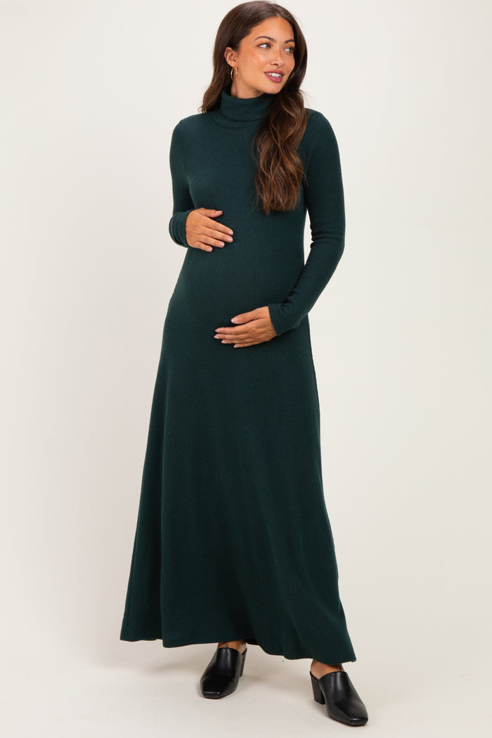 woman wearing a dark green long sleeve maternity maxi dress while holding her baby bump