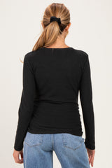 woman wearing a black long sleeve maternity top, seen from the back, paired with light blue jeans