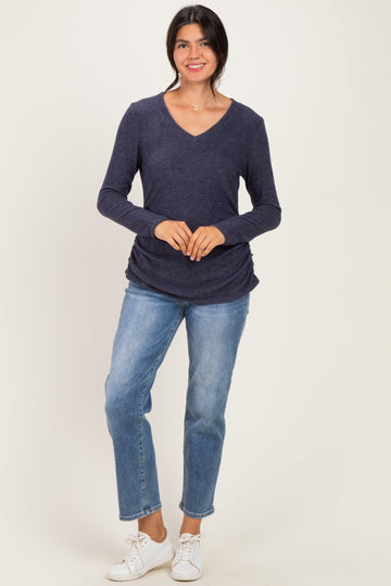 woman wearing a navy long sleeve v-neck top with a relaxed fit and light blue jeans, standing and smiling