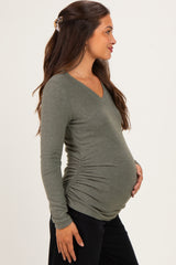 woman wearing an olive green long sleeve maternity top with side ruching and showing her baby bump