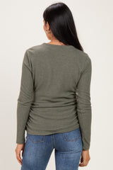 woman wearing a dark green long sleeve top with a fitted design, viewed from the back with blue jeans.