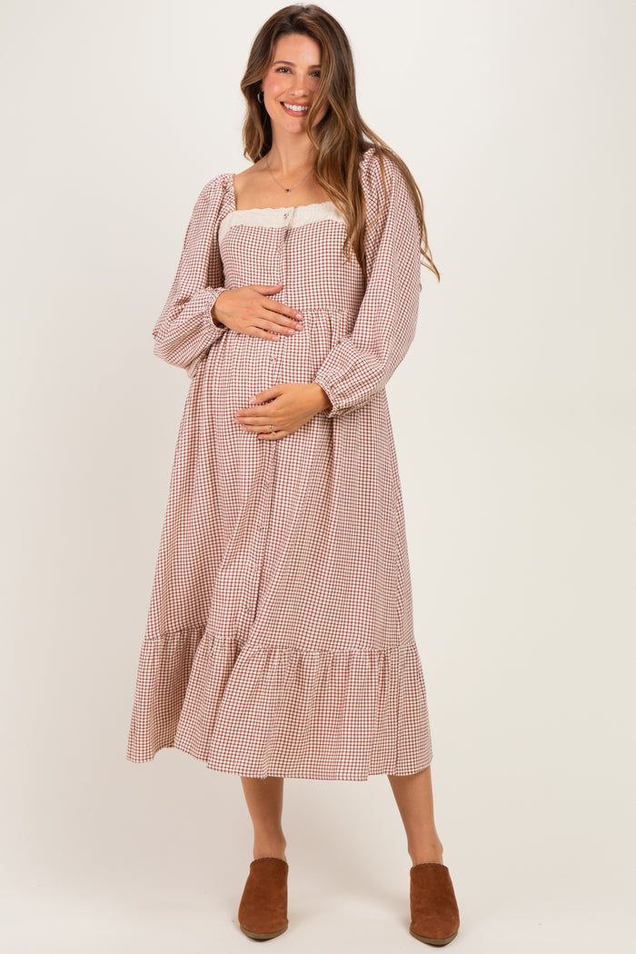 woman wearing a brown and cream checkered maternity dress with puff sleeves and a tiered skirt, holding her baby bump