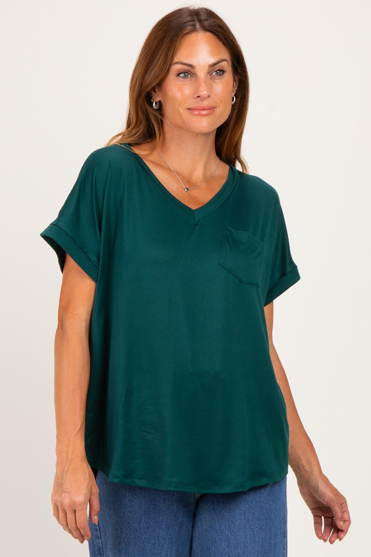 woman wearing a dark green short sleeve v-neck top with a front pocket and relaxed fit