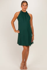 woman wearing a dark green halter neck maternity dress with a flowing silhouette and a baby bump visible