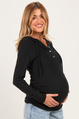 woman wearing a black maternity hoodie with a button-up design and a visible baby bump