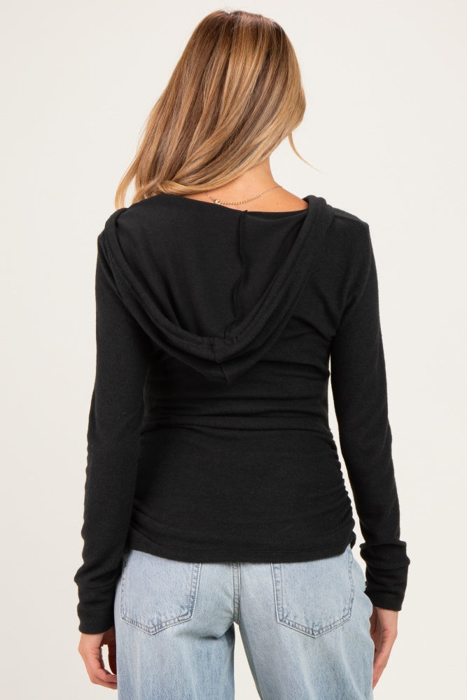 woman wearing a black maternity hoodie with a fitted design and gathered sides, showing a relaxed back view