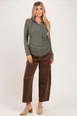 woman wearing an olive green long sleeve hooded henley top with buttons and brown wide leg corduroy pants