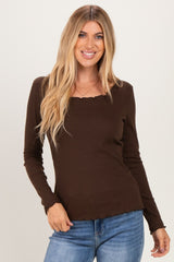 woman wearing a brown long sleeve top with a square neck and scalloped hem, smiling at the camera