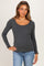woman wearing a gray long sleeve maternity top with a scalloped neckline and holding her baby bump