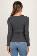 woman wearing a dark gray long sleeve maternity top with scalloped edges, seen from the back