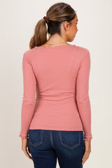 woman wearing a light pink long sleeve maternity top, viewed from the back, paired with dark blue jeans