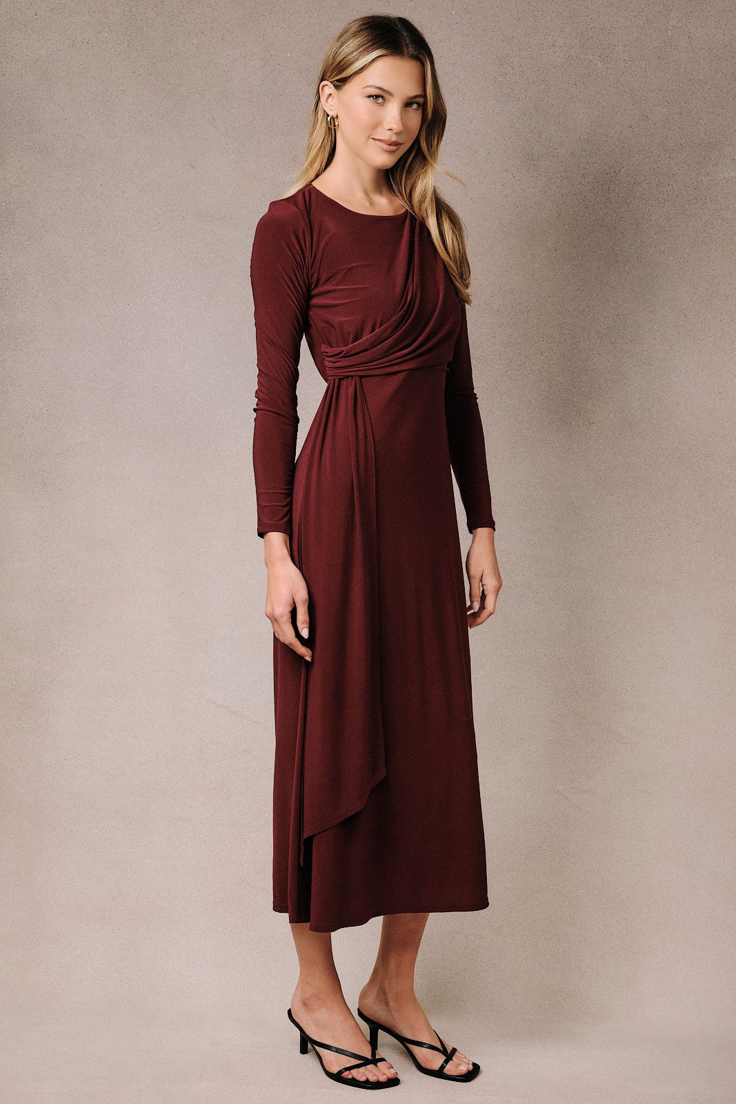 woman wearing a burgundy long sleeve wrap dress with a draped bodice and a flowy skirt