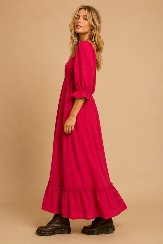 woman wearing a bright pink maxi dress with puff sleeves and ruffle hem, styled with black ankle boots