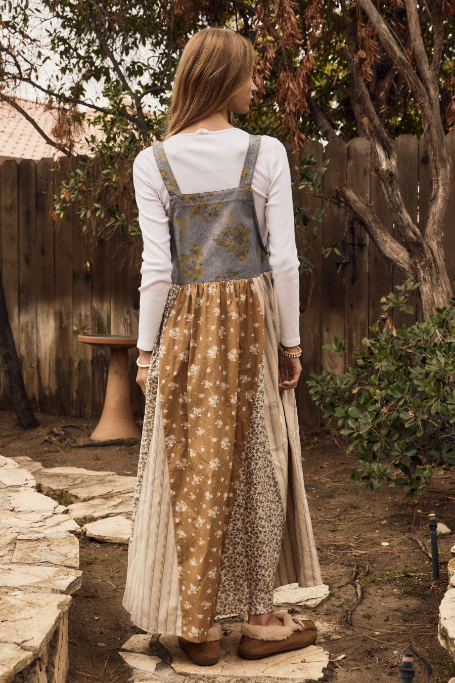 woman wearing a long patchwork maxi dress with a denim bodice and various floral patterns on the skirt