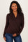 woman wearing a dark brown long sleeve maternity top and gently holding her baby bump