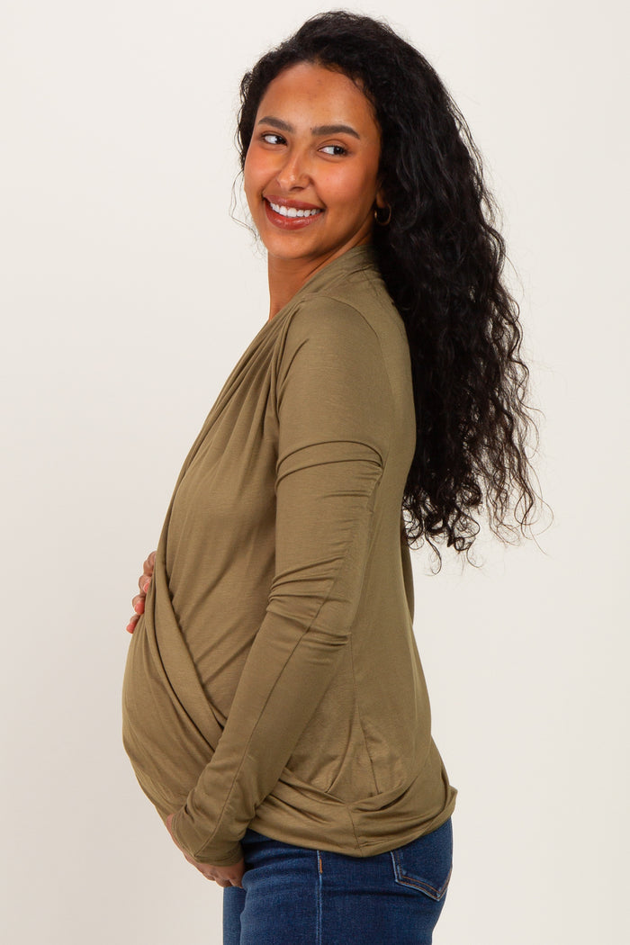 woman wearing an olive green wrap maternity top and holding her baby bump