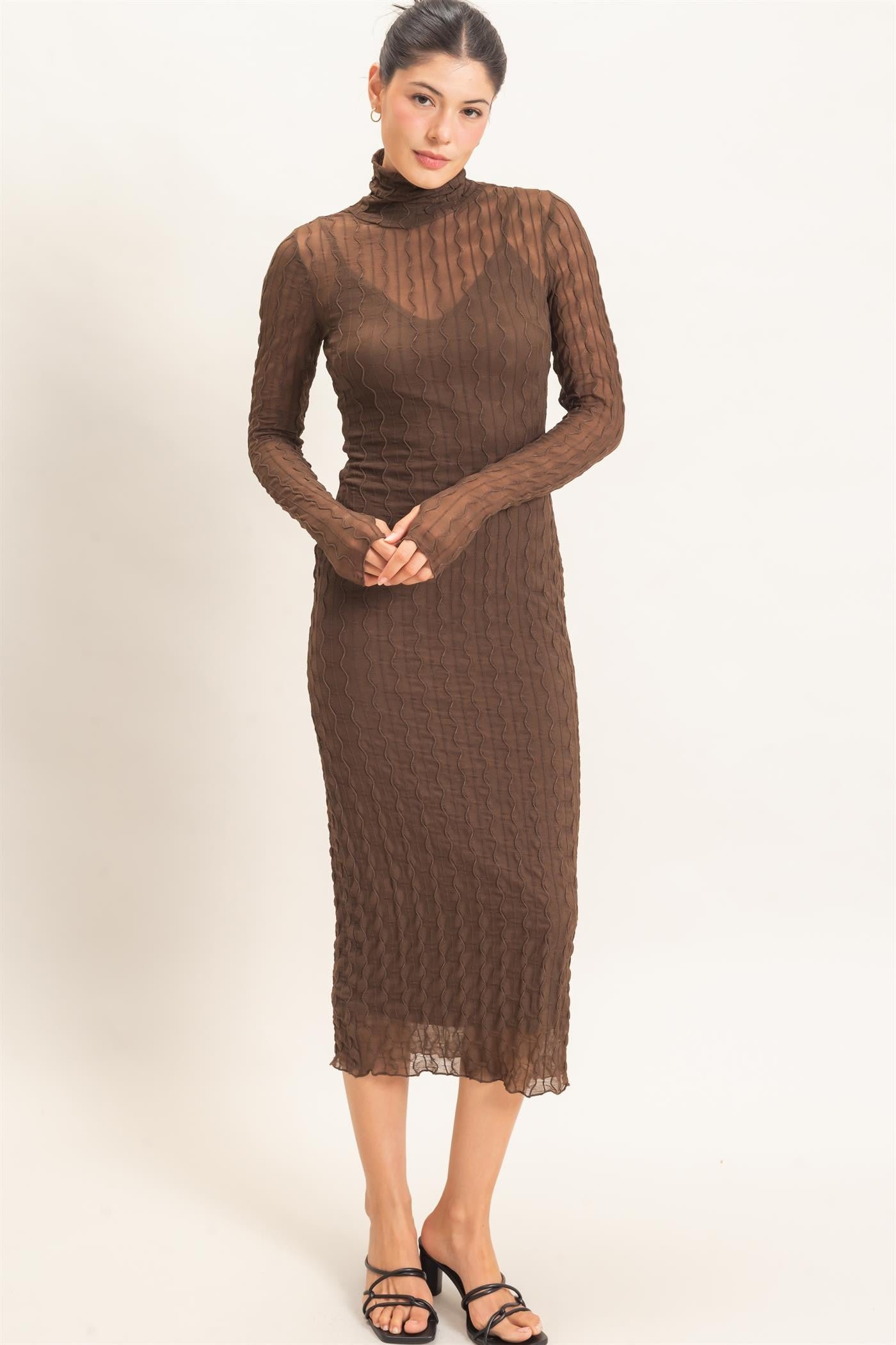 woman wearing a brown sheer long sleeve midi dress with a turtleneck and textured design