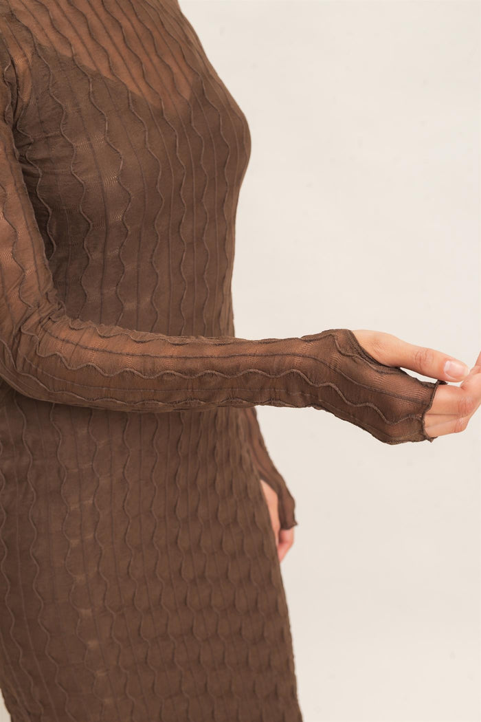 woman wearing a brown sheer long sleeve dress with a textured wavy pattern and thumbhole cuff details