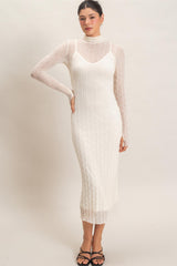 woman wearing a white ribbed knit maxi dress layered with a sheer long sleeve turtleneck top and strappy black sandals