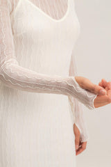 woman wearing a white long sleeve dress with wave pattern and sheer sleeves