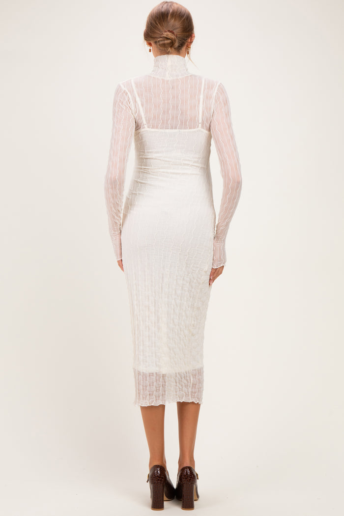 woman wearing a white maternity dress with long sleeves and a fitted silhouette, showing a baby bump from the back