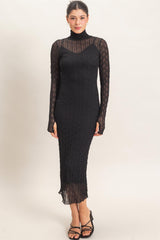 woman wearing a black long sleeve ribbed knit dress with a high neckline and form-fitting silhouette