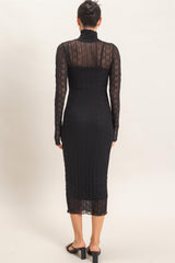woman wearing a black long sleeve fitted midi dress with a sheer back and textured detailing