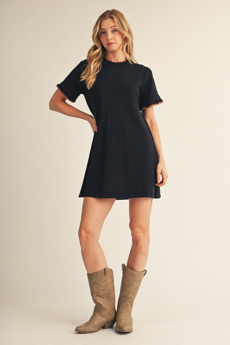 woman wearing a black short sleeve dress with ruffled sleeves and cowboy boots