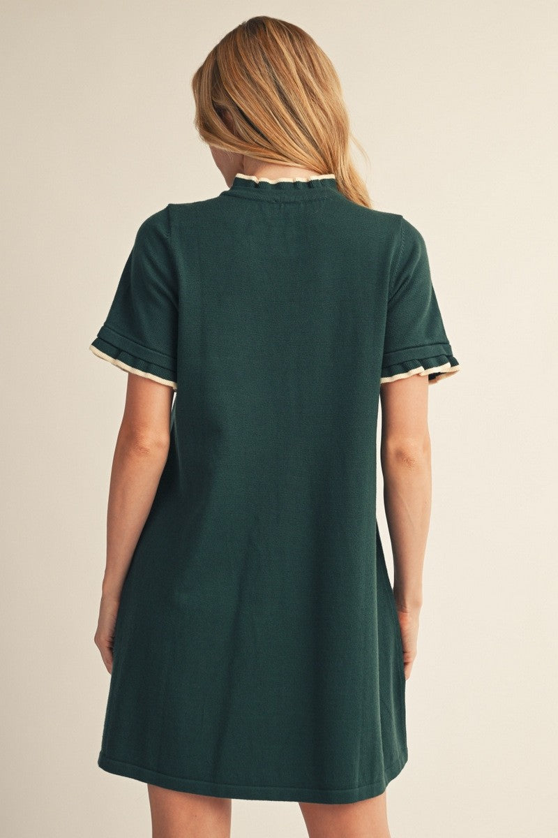 back view of a woman wearing a dark green short sleeve dress with scalloped detail on the sleeves