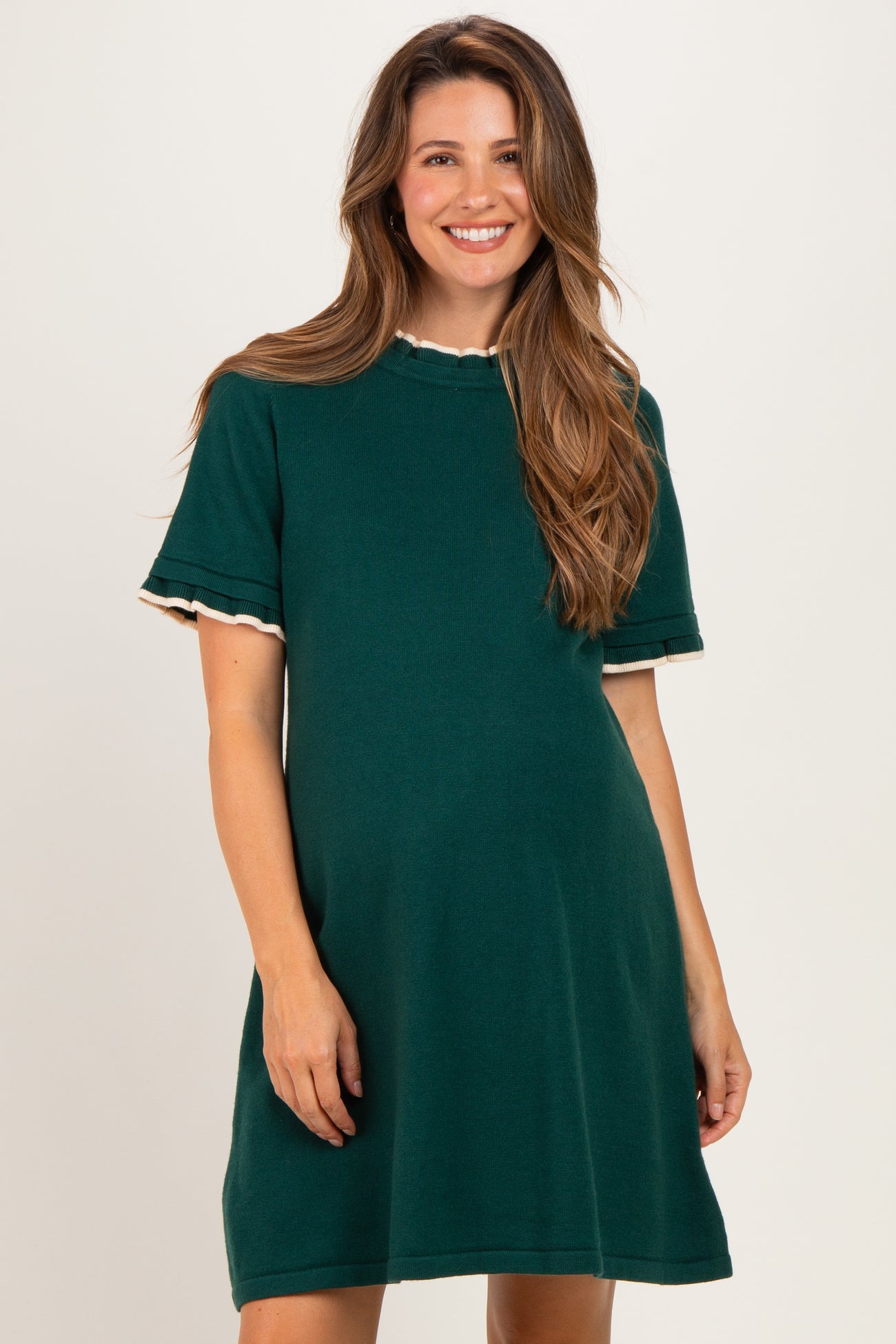 woman wearing a dark green short sleeve maternity dress with scalloped trim detailing