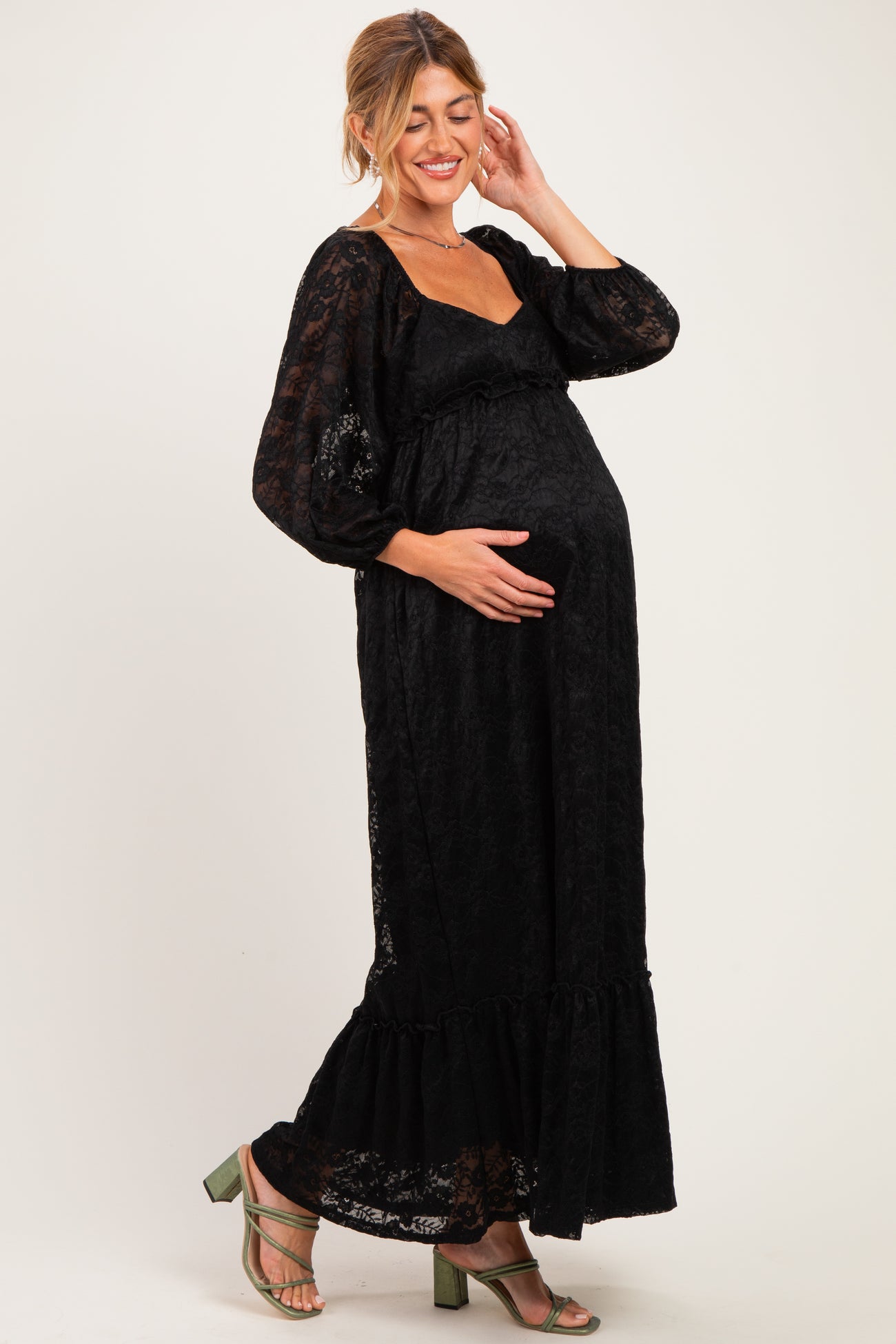 woman wearing a black lace maternity maxi dress with long sleeves and a baby bump