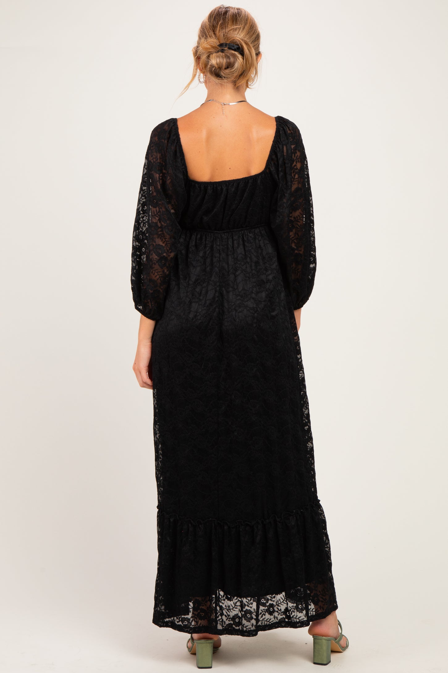 woman wearing a black lace maternity maxi dress with a square neckline and puffed sleeves, showing a baby bump