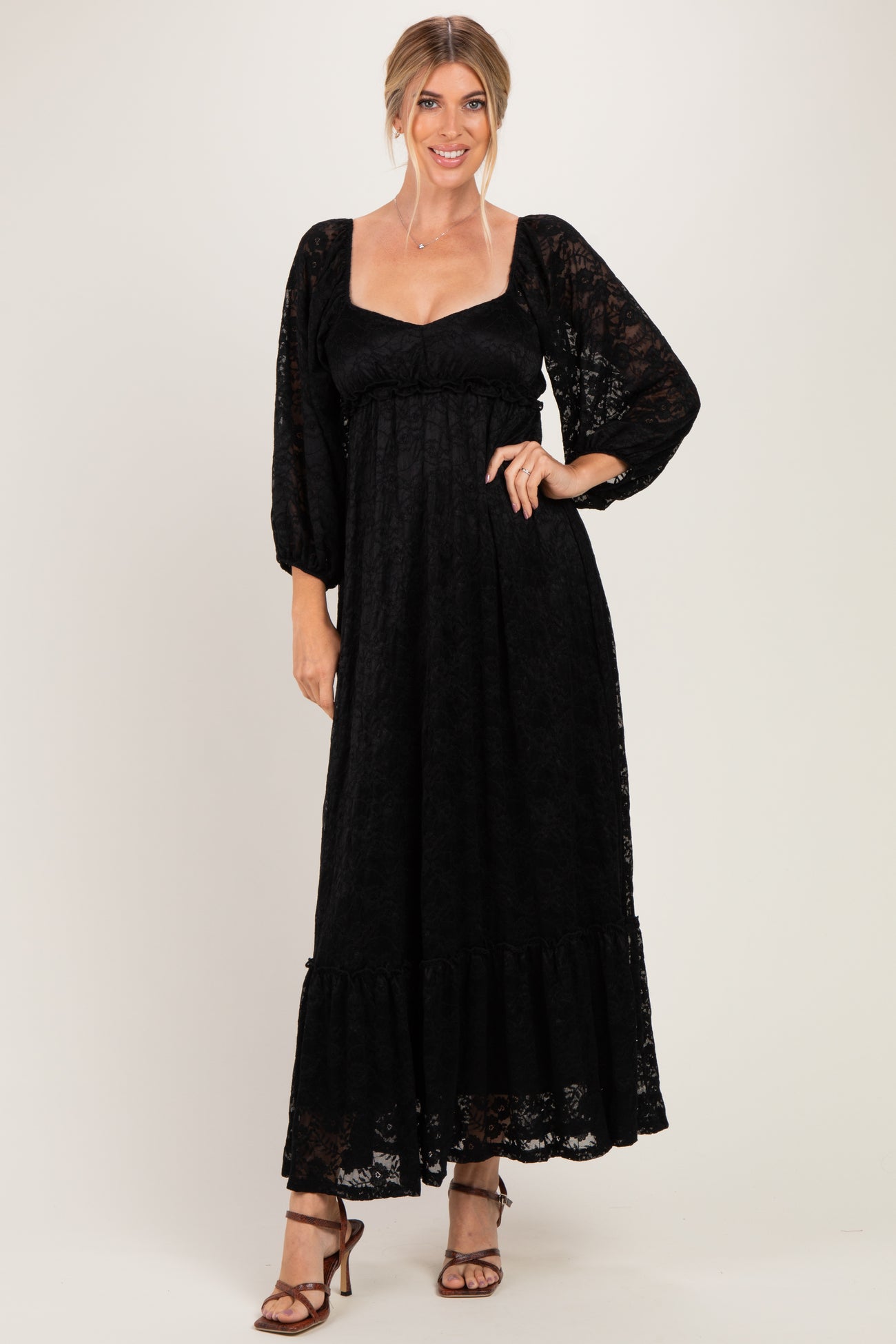 woman wearing a black lace maxi dress with long puff sleeves and a ruffled hemline