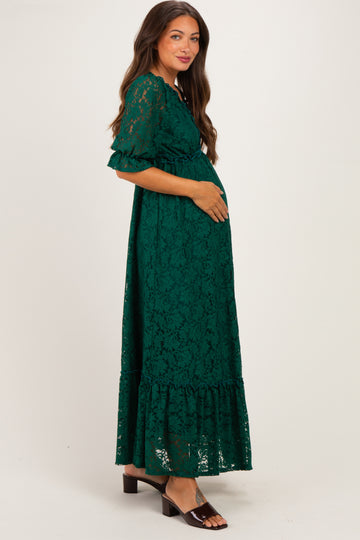 woman wearing a green lace maternity maxi dress and holding her baby bump