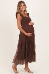 woman wearing a brown tiered maternity dress with ruffle straps and holding her baby bump