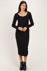 woman wearing a black long sleeve midi dress with a scoop neckline and a fitted silhouette