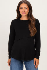 woman wearing a black long sleeve maternity top with a layered design and a visible baby bump