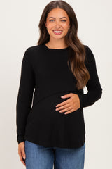 woman wearing a black long sleeve maternity top and holding her baby bump