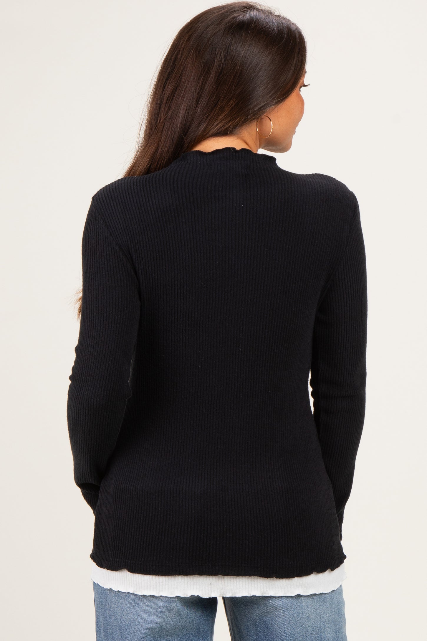 woman wearing a black ribbed maternity top with long sleeves and a scalloped neckline, view from the back