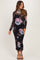 woman wearing a black floral maternity dress with long sleeves and a fitted silhouette