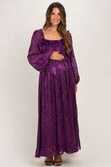 woman wearing a purple floral long sleeve maternity dress and holding her baby bump